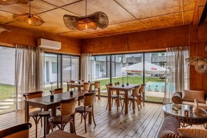 A spacious indoor area with wooden flooring, tables, and chairs arranged for dining. Large windows provide views of the outside. - La Perla (Chihuahua)