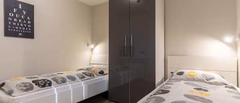 Quarto com cama, guarda-roupa e luminária na parede.