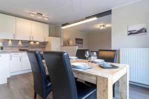 Una cucina moderna con mobili bianchi, un tavolo da pranzo in legno e sedie nere.