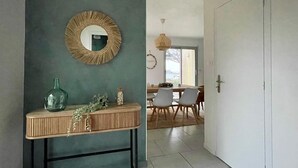A modern interior with a round mirror, a wooden console table, and a dining area with chairs and a hanging light fixture. - Holiday Home in Terenez with Sea Views (Plougasnou)