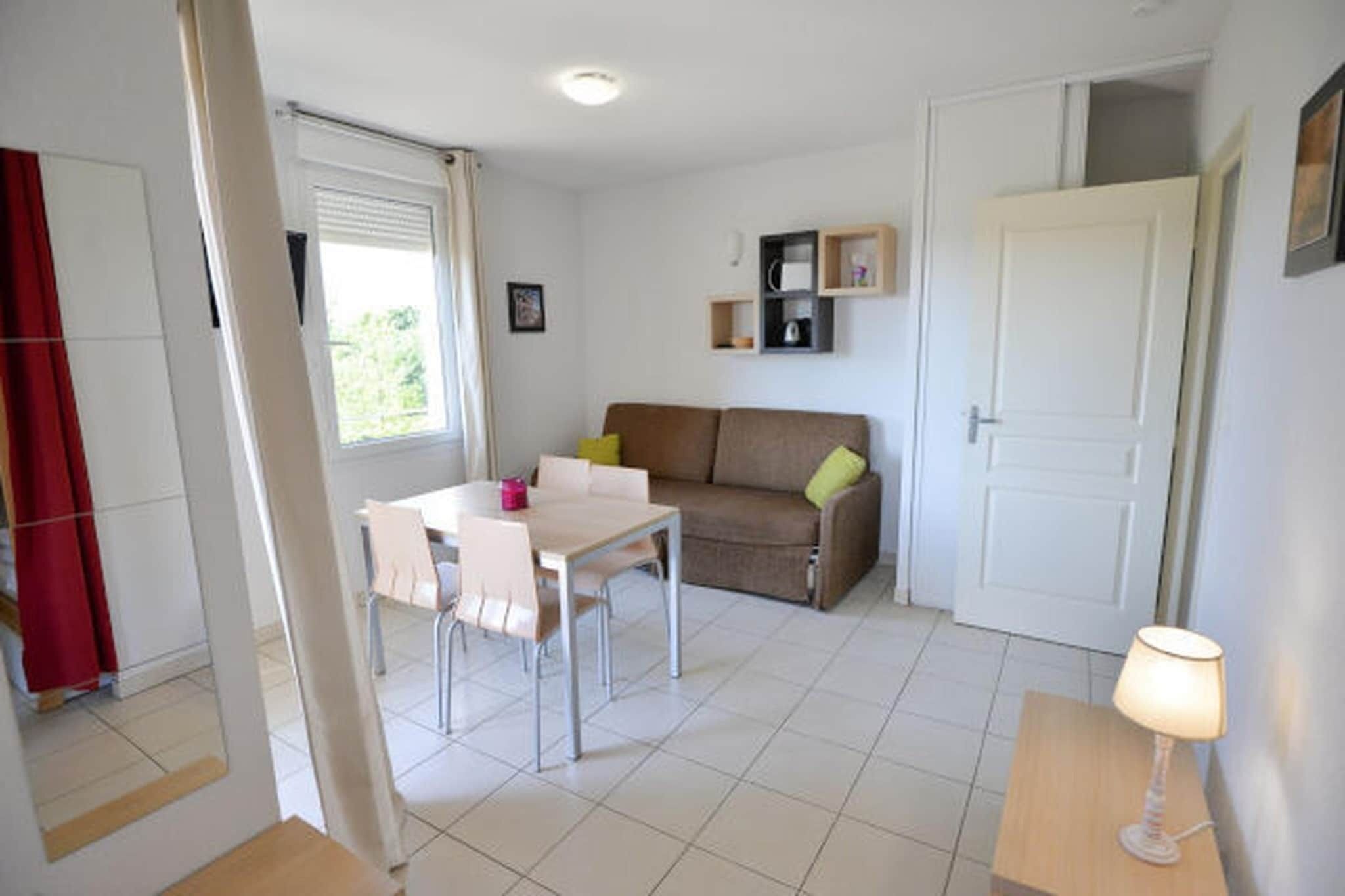 Une pièce comprenant une table à manger, des chaises, un canapé, une lampe et une porte.