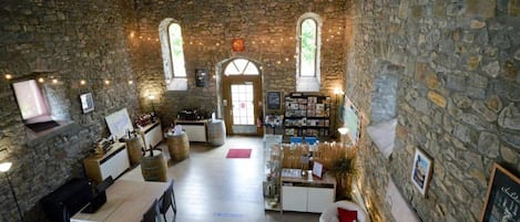 A rustic interior with stone walls, a wooden ceiling, a dining area with a table and chairs, a bar area with bottles, and a fireplace.