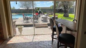 Eine Terrasse mit Pool, Gartenmöbeln und einer Bar.