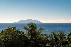 A tropical beach with palm trees and a mountain in the background. - Villa Panoramic Seaview (Mahé Island)