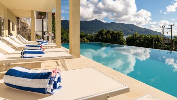 Un espace aménagé au bord de la piscine, avec des chaises longues et des serviettes, offrant une vue sur une chaîne de montagnes.