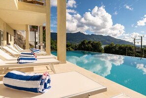 Ein Poolbereich mit Liegestühlen und Handtüchern mit Blick auf ein Gebirge.