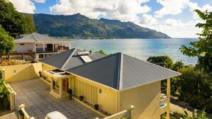 Une propriété située en bord de mer, dotée d’un grand patio, d’un espace extérieur couvert aménagé en salon et offrant une vue sur la mer et les montagnes.