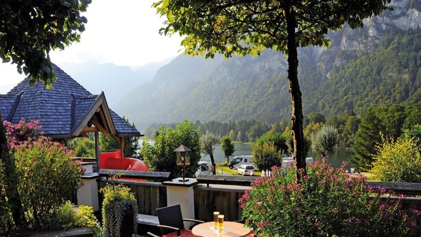 An outdoor patio with a table and chairs, overlooking a lake and mountains. - Chalet in Tyrol near Ski Slopes (Kramsach)