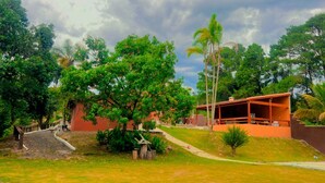 Un edificio de fachada roja, rodeado de exuberante vegetación y árboles.