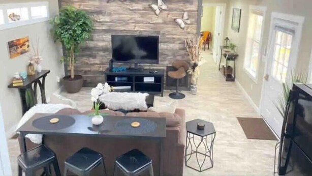 A spacious living area with a stone wall, a flat-screen TV, a dining table with chairs, and a cozy seating area. - Mountain Hideaway - HOT TUB (Horse Shoe)