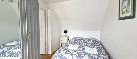 A bedroom with a large bed, a bedside table with a lamp, and a mirror.