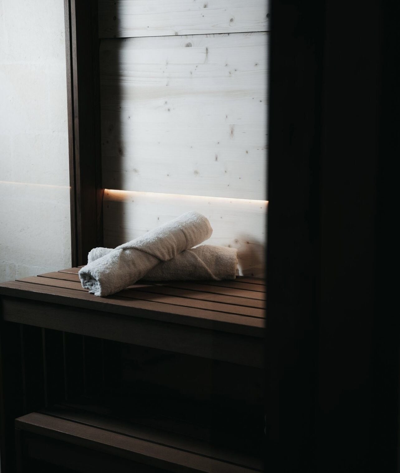Une fenêtre avec un banc en bois et une serviette pliée posée dessus.