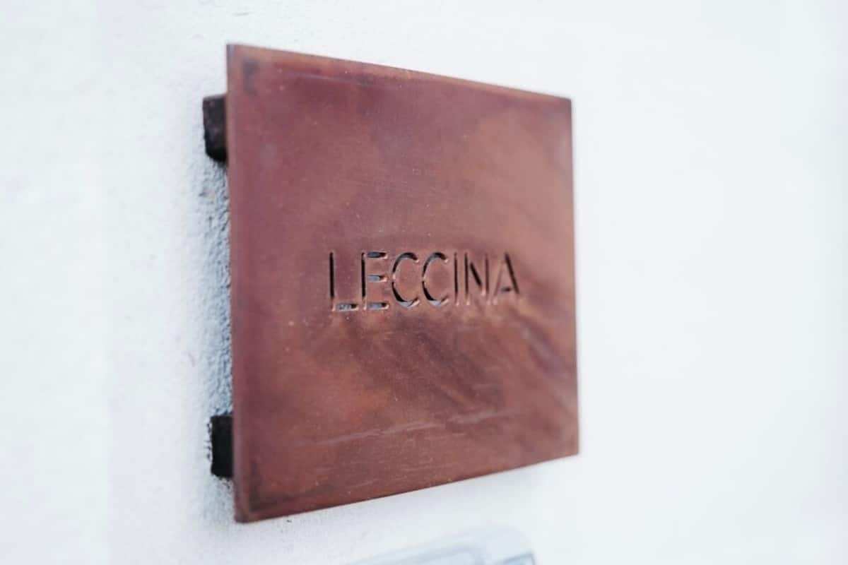 Eine Plakette mit dem erhabenen Schriftzug 'LECCINA' an einer Wand.