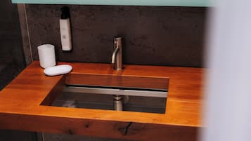 A bathroom with a wooden vanity, a sink, a faucet, and a soap dispenser.