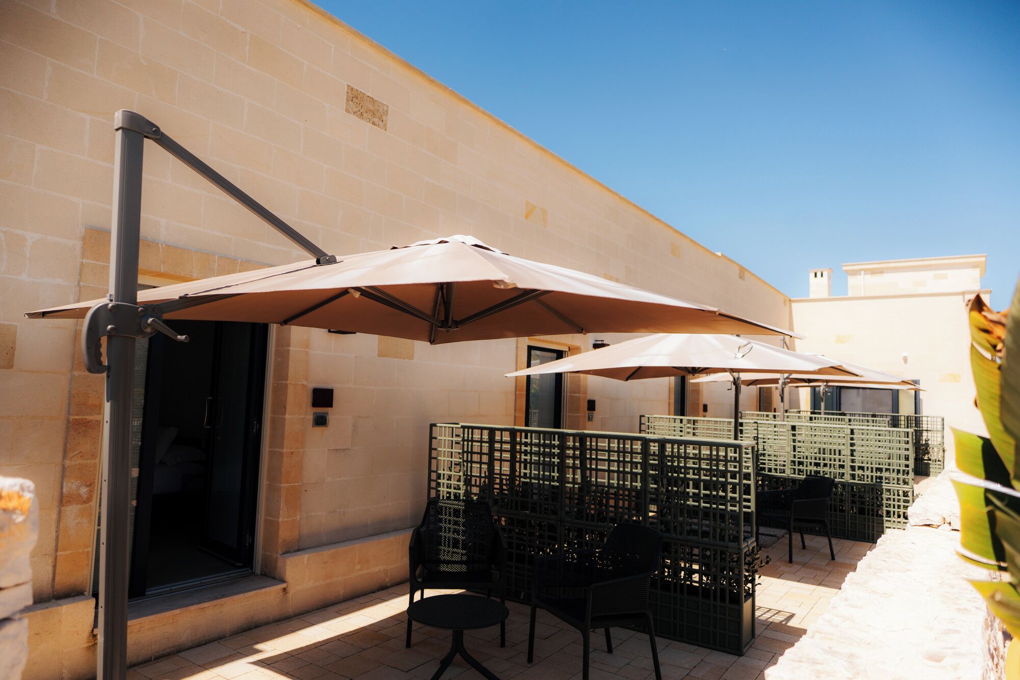 Outdoor seating with umbrellas, a brick wall, and a clear sky.