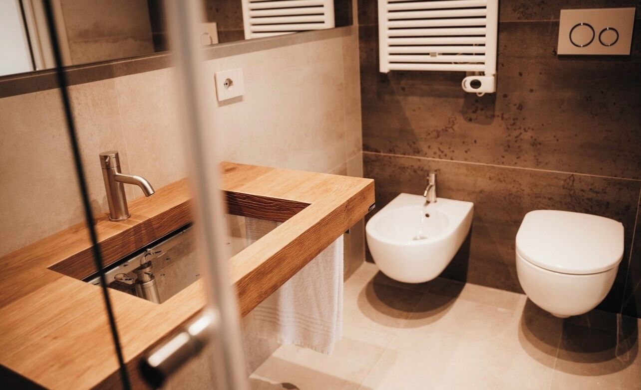 Ein modernes Badezimmer mit einem Holzkosmetikschrank, einem Bidet und einer Toilette.