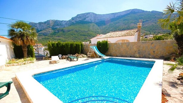A swimming pool with a clear blue water, surrounded by a stone wall, palm trees, and a mountain view in the background. - SAONA VILLAS (AS CHARL): villa for 8 people, private swimming pool, air co (Dénia)