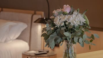 Habitación de hotel ordenada con una mesita de noche que sostiene un libro y un florero.