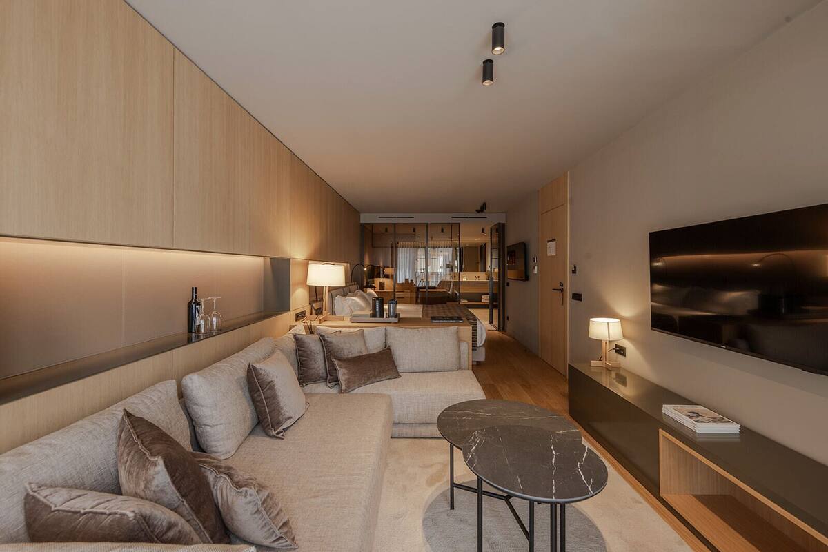 Une chambre d’hôtel moderne équipée d’un canapé, d’une petite table, d’une télévision et d’un mini-bar.
