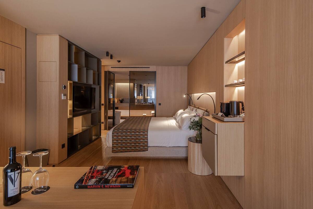 Une chambre d’hôtel moderne équipée d’un lit, d’une table de chevet, d’une télévision et d’une petite kitchenette.