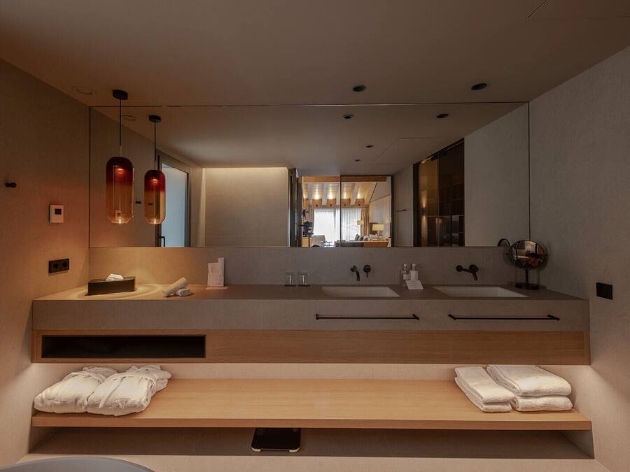 Ein modernes Badezimmer mit einem großen Spiegel, zwei Waschbecken und einer Holzausstattung.