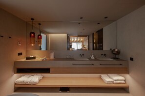 Une salle de bain moderne avec un grand miroir, deux vasques et un meuble-lavabo en bois.