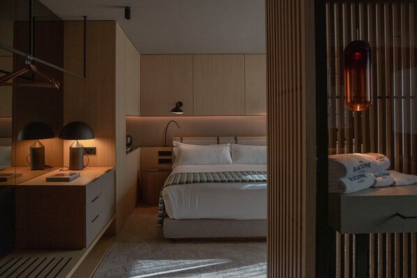 Un dormitorio moderno con cama, mesitas de noche y una lámpara colgante.