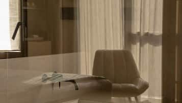 Un baño moderno con un espejo grande, un lavamanos y una silla.