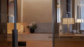 Une salle de bain moderne avec un grand miroir, une plante en pot et un meuble-lavabo en bois.