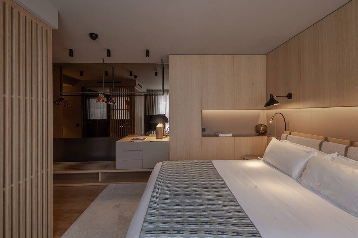 Une chambre moderne avec un grand lit, des tables de chevet, un bureau et une armoire.
