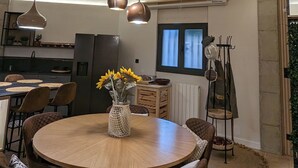 En matplats med ett runt träbord, bruna stoppade stolar och en vas med solrosor.