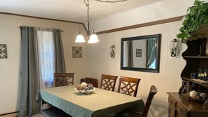 Comedor con una mesa preparada para cuatro, un banco y un aparador con objetos decorativos.