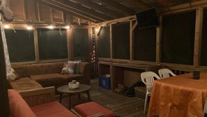 Una terraza al aire libre con muebles de madera, incluyendo un sofá, sillas y una mesa.