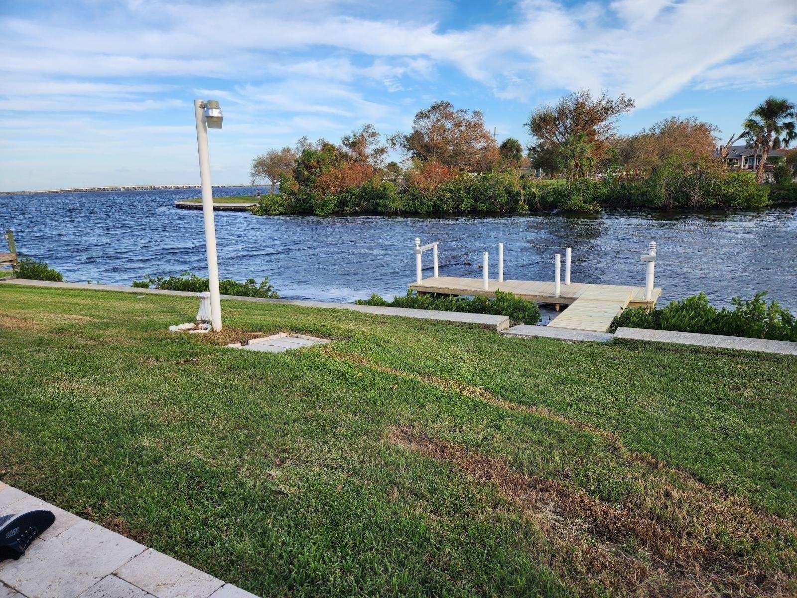 Un parque junto al agua con un muelle de madera, una farola y una zona cubierta de césped.