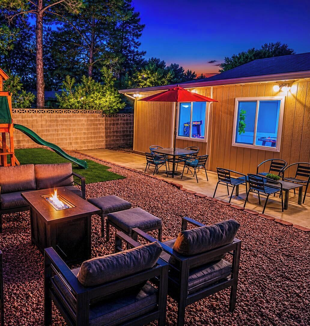 Un jardin avec un foyer extérieur, du mobilier de jardin, un toboggan et une terrasse en bois.