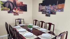 Ein Esszimmer mit einem runden Tisch, gedeckt für sechs Personen, umgeben von Holzstühlen.