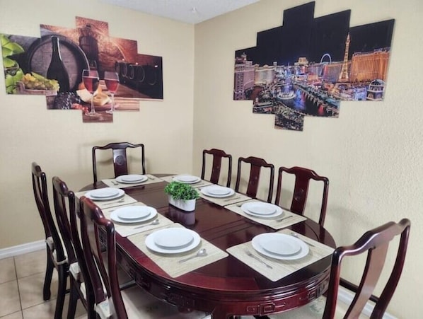 Ein Esszimmer mit einem runden Tisch, gedeckt für sechs Personen, umgeben von Holzstühlen.