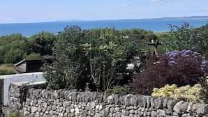 A stone wall with a view of the sea and distant mountains.