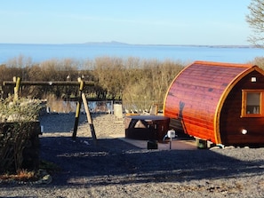 Een houten chalet met een klein raam, een schommel en een picknicktafel.
