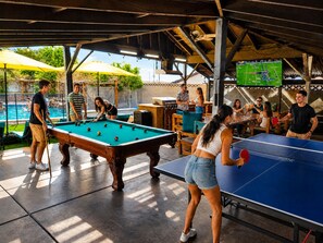 An indoor recreational area with a pool table, a ping pong table, and a television screen displaying a sports game. - 2-Connected Villas Luxury Vacation Villa 5,250sqft with FREE Heated pool
 (Las Vegas)