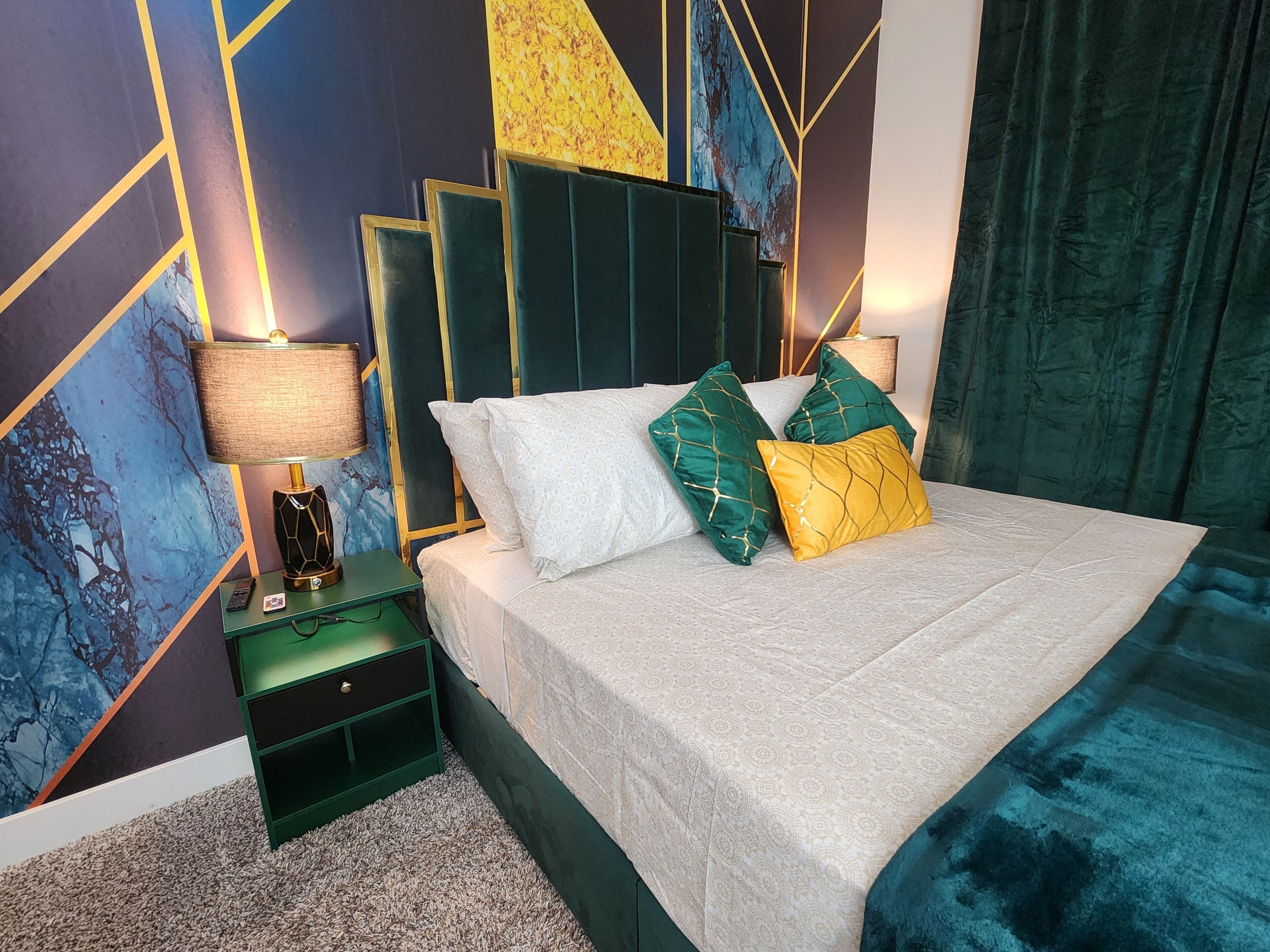 Un dormitorio moderno con cama, mesita de noche verde y una lámpara.