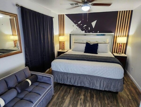 A hotel room with a large bed, a sofa, a ceiling fan, and a wall with a decorative pattern. - 2-Connected Villas Luxury Vacation Villa 5,250sqft with FREE Heated pool
(Las Vegas)