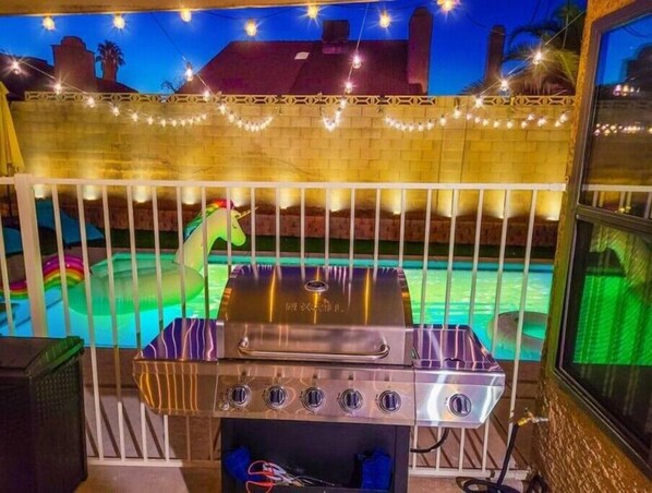 Un barbecue extérieur, avec une piscine et un grand flotteur gonflable en forme de licorne en arrière-plan.