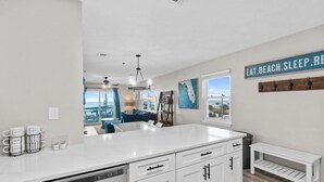Una cocina moderna con armarios blancos, una isla grande y vistas al área de estar.