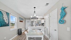 Una cocina moderna con armarios blancos, un refrigerador de acero inoxidable y una lámpara colgante.