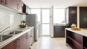 A modern kitchen with stainless steel appliances, dark wooden cabinets, and a large window providing natural light.
