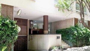 A modern building entrance with a concrete pillar, a staircase, and greenery.