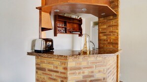 A kitchen with a brick island, a wooden shelf, and a glass-top coffee table. - Paris Marais Best WE MERRIS (Paris)
