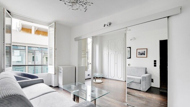 A modern living room with a glass coffee table, grey sofas, and a large mirror reflecting the space. - Paris Marais Best Trip (Paris)
