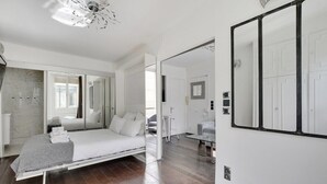 A modern bedroom with a bed, a large mirror, and a walk-in closet. - Paris Marais Best Trip (Paris)